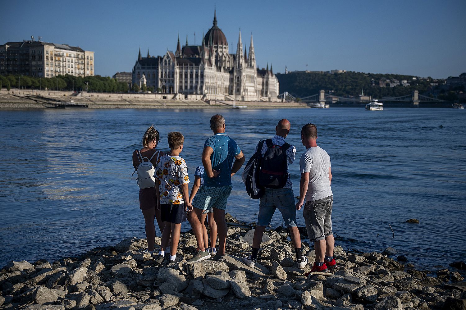 Emberek nézik a Duna kiszáradó medréből a Parlamentet Budapesten