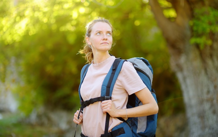 Young woman hiking in countryside Backpacking hike - Startlap Utazás Erdőben túrázó, hátizsákos fiatal nő figyel valamire. medvék kiváló hallással és szaglással rendelkeznek.