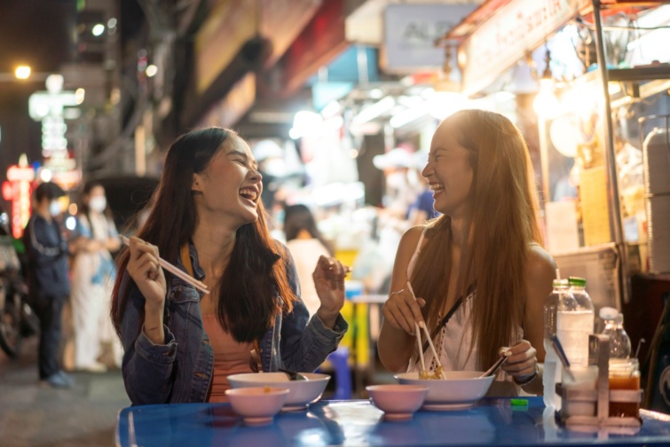 steet food - Startlap Utazás 2 lány élvezi egymás társaságát az utcán, miközben helyi fogásokat kóstolnak.
