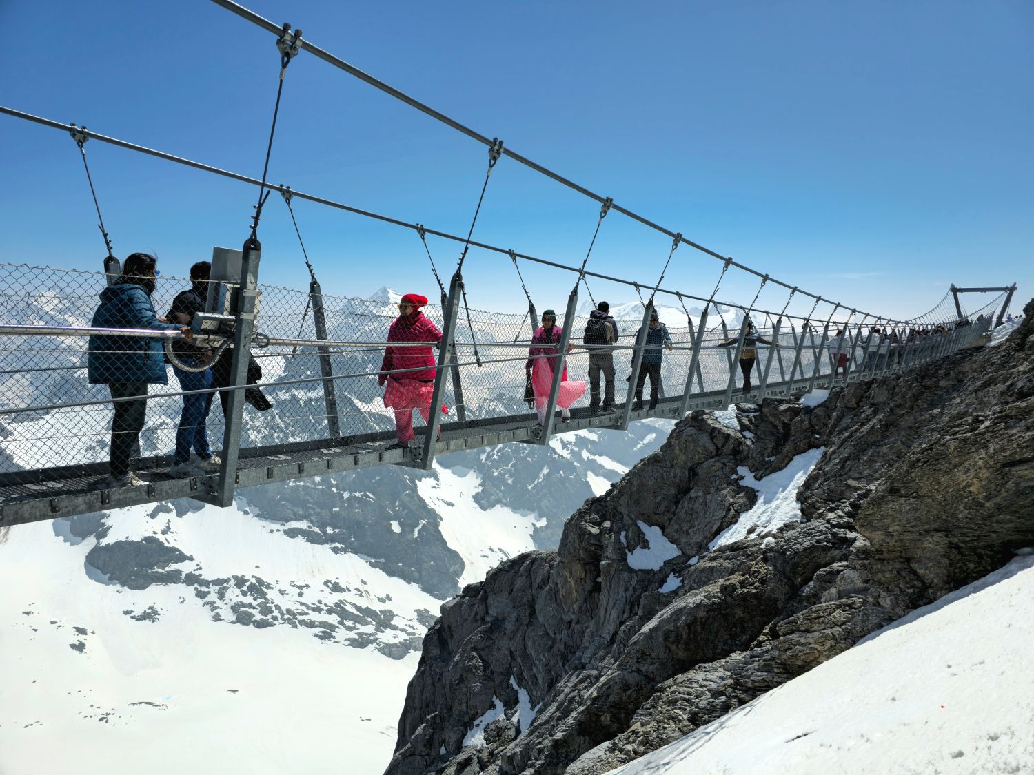 A hídon sétáló turisták a csodás tájat viszgálják.