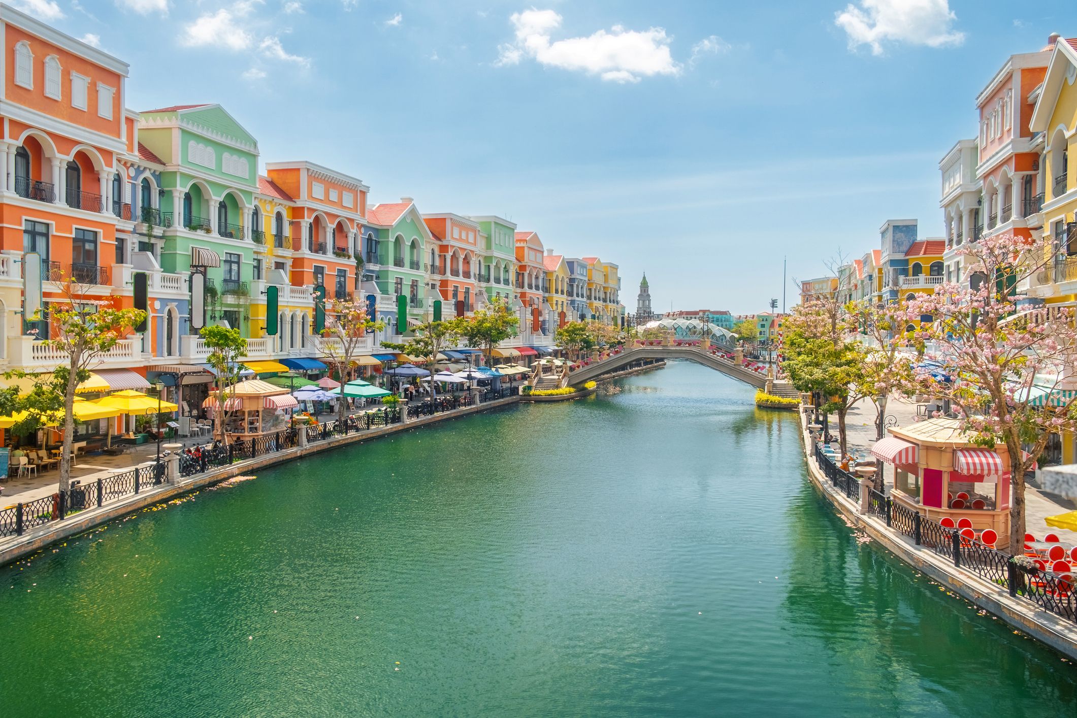 Színes, mediterrán stílusú épületek a Grand Canal mentén, híddal a vietnámi Phu Quoc szigeten. Grand World városrész nyüzsgő kávézókkal, üzletekkel és virágzó fákkal.