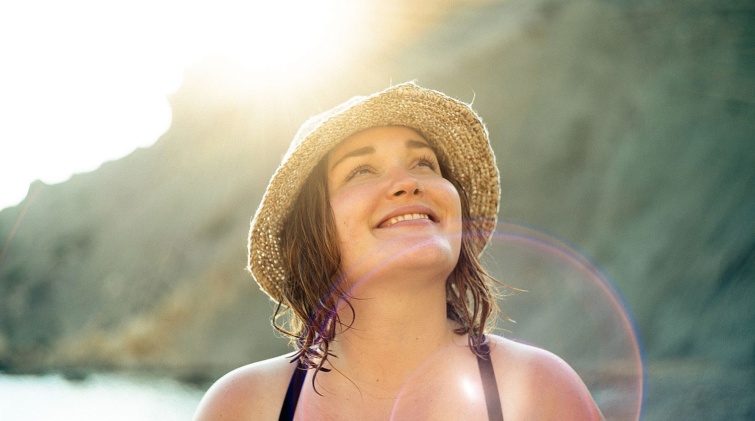 Young woman smiling at the beach - Startlap Utazás Fiatal mosolygó nő napfényben, tengerparton.