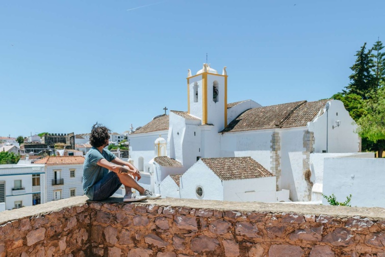 férfi ül egy padkán mediterrán városkában