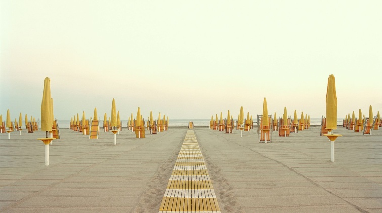 Italy Rome Ostia closed beach parasols and walkway - Startlap Utazás Üres tengerparti strand lecsukott sárga napernyőkkel.