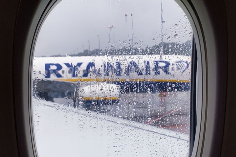 ryanair_eso_ - Startlap Utazás Ryanair repülőgépe az ablakon át esőcseppeken keresztül látható a belgiumi Charleroi repülőtéren,