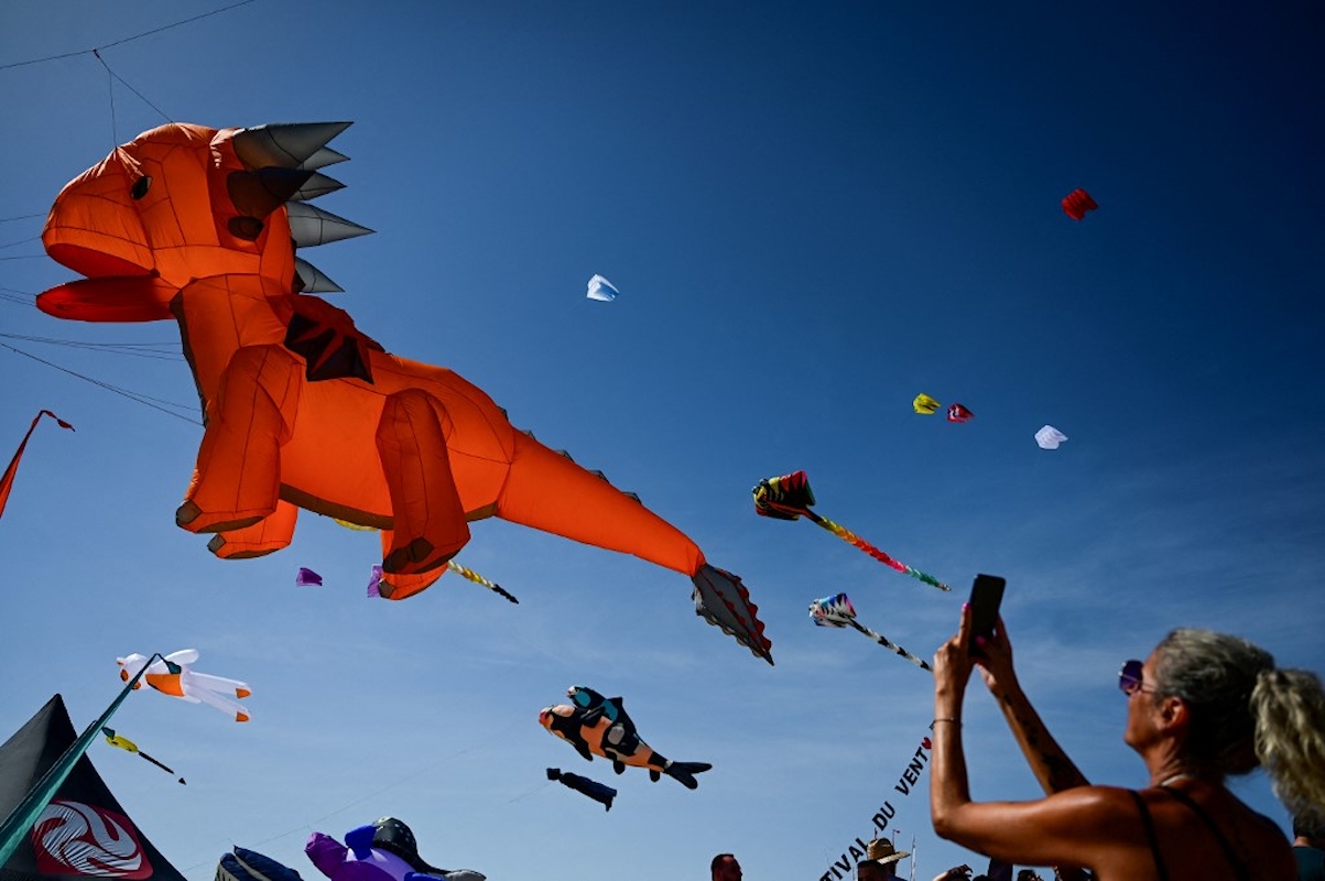 Egy nő sárkányrepülőket fényképez a Festival du Vent (Szélfesztivál) alatt a dél-franciaországi Portiragnes-Plage-ban, 2026. szeptember 6-án