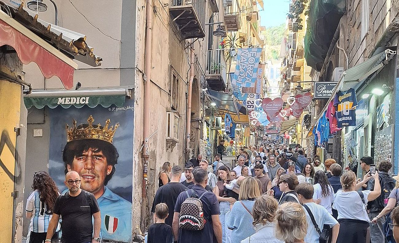 napoly-20 - Startlap Utazás Maradona-falfestmény egy emberekkel teli nápolyi utcában.