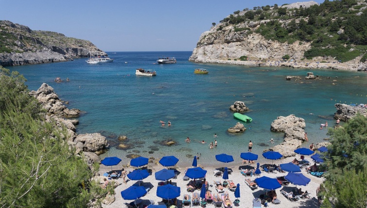 Egy mediterrán tengerparti strand, öböl kék napernyőkkel