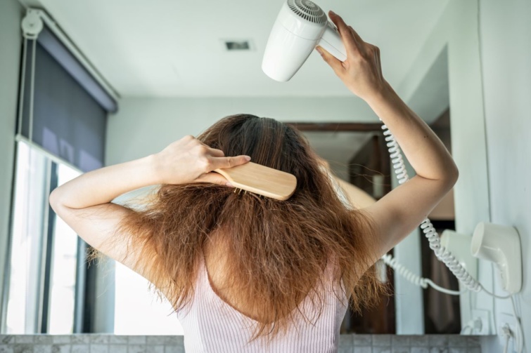 Egy nő hajat szárít egy fésű segítségével