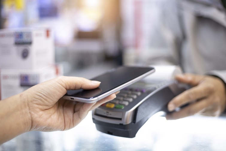 Valaki a mobiltelefonjával fizet egy bankkártyaterminálon keresztül