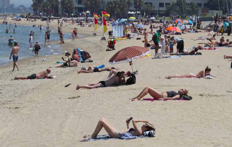 Napozók a hőségben a melbourne-i St. Kilda strandon.