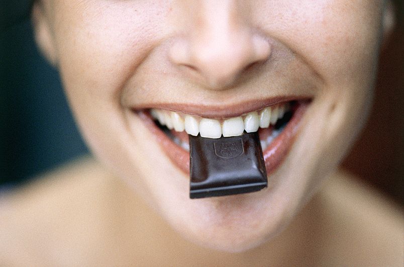 Nő a szájában egy kocka csokival