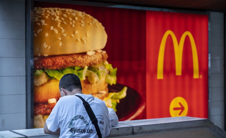 Egy férfi áll a McDonald's plakátja előtt.