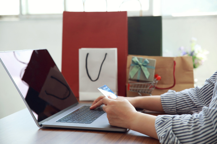 Egy nő bankkártyával és laptoppal, ajándékokkal 
