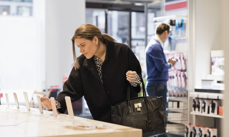 Egy vásárló nő kipróbál egy mobiltelefont a mobiltelefon-szaküzletben.