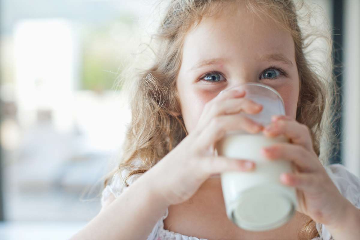 Pohár tejből kortyoló kislány
