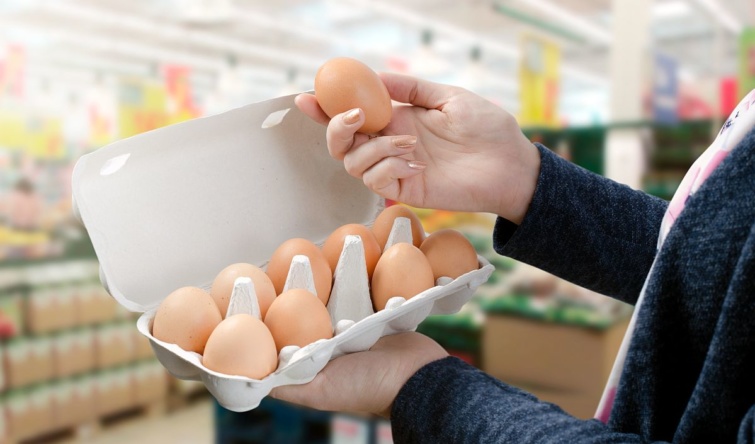 Egy vásárló egy doboz tojást tart a kezében a boltban.