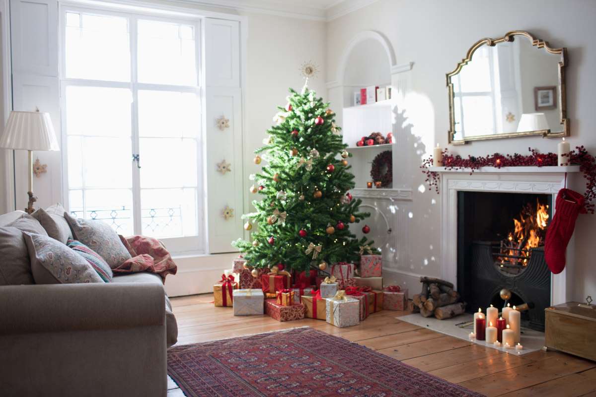 Feldíszített karácsonyfa egy kandalló előtt