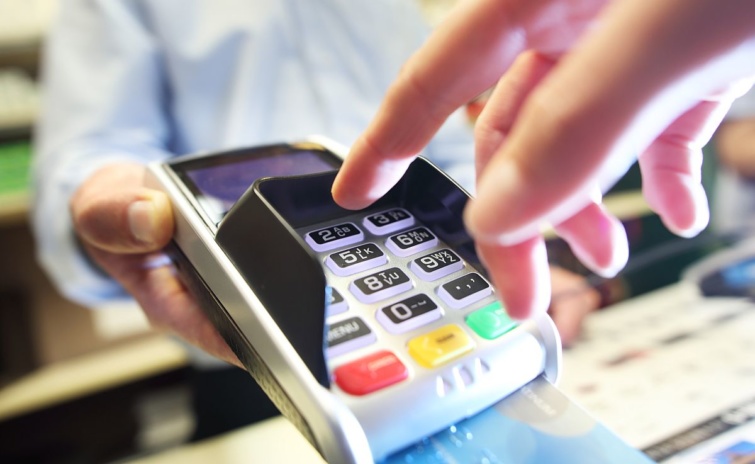 PIN-kódot üt be egy ember bankkártyás vásárlásnál.