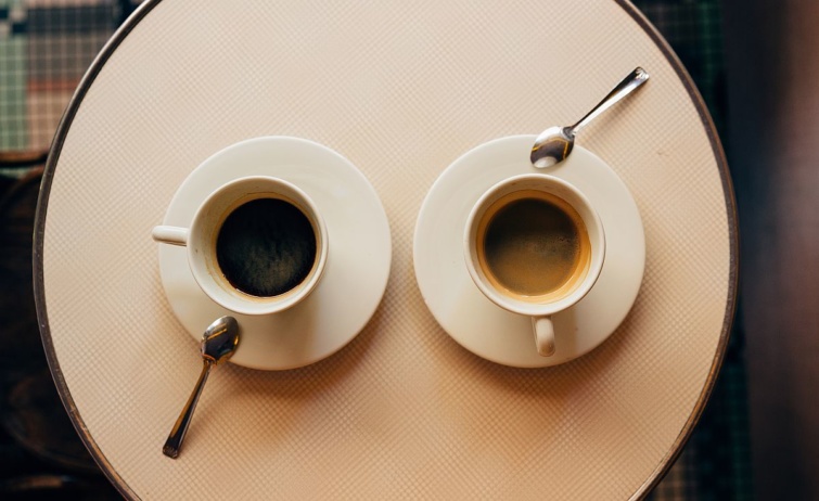 Két csésze kávé kiskanállal egy asztalon.