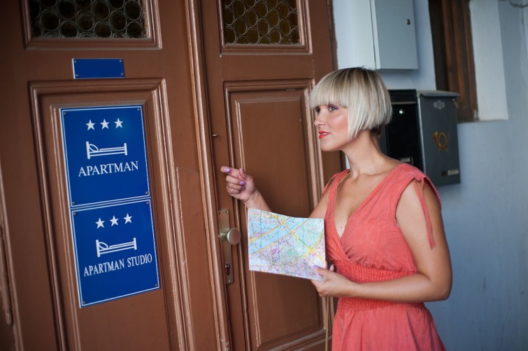 Egy nő kopogtat egy szálláshely ajtaján.