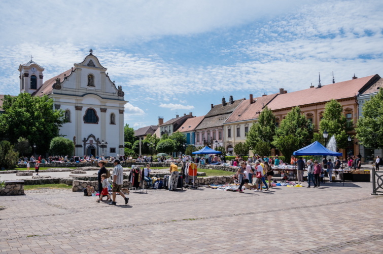 Bolhapiacra kilátogató érdeklődő helyi lakosok és turisták Vácon a Március 15. téren. Háttérben a Fehérek temploma, amit 1755-ben Szűz Mária tiszteletére szenteltek fel. Eredetileg a domonkos rendhez, az ún. "fehér barátokhoz" tartozott, ez alapján kapta a nevét.