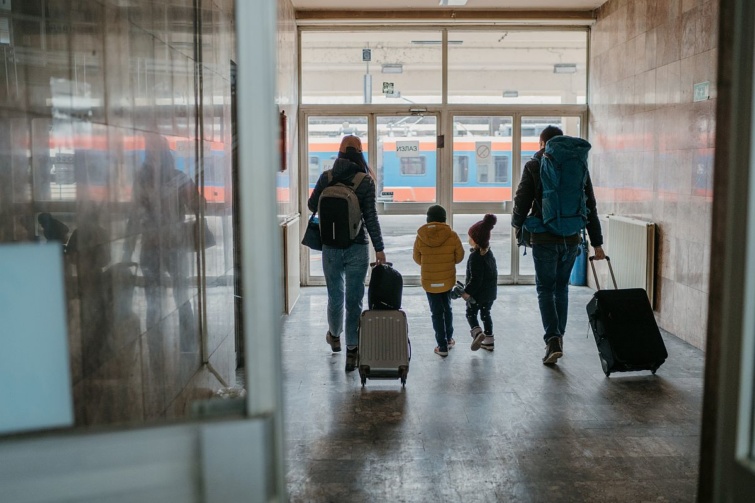 Egy négytagú család bőröndökkel a pályaudvaron.