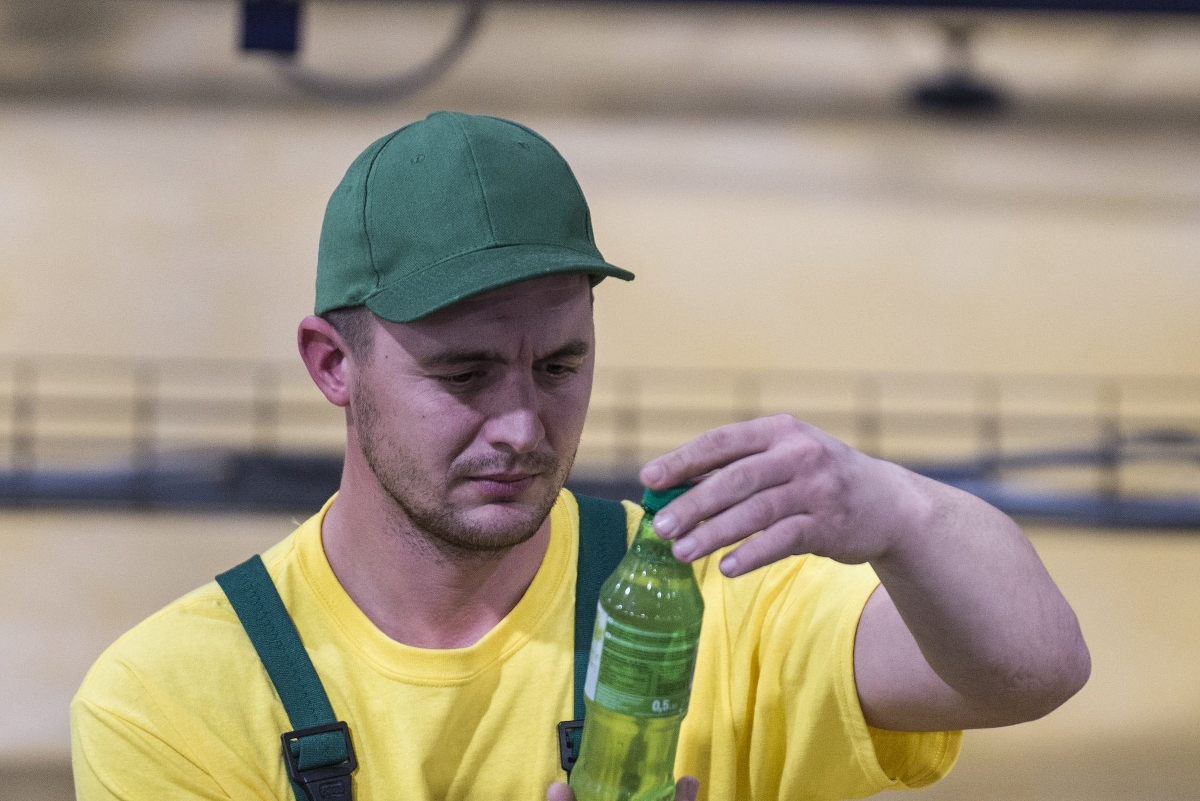 Szakember ellenőriz egy palackot a futószalag mellett a Márka Üdítőgyártó Kft. üzemében