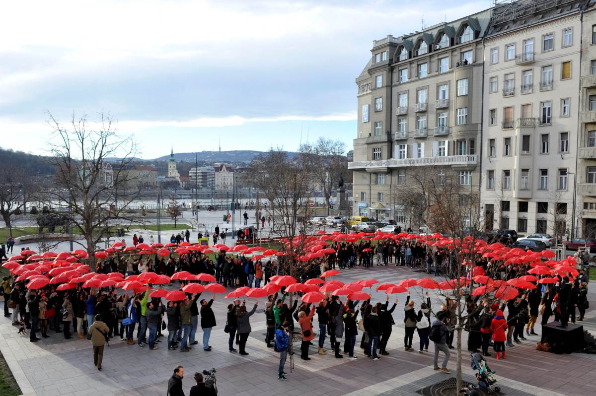 Piros esernyőt tartanak a Valentin-napi flashmob résztvevői Budapesten a Március 15. téren