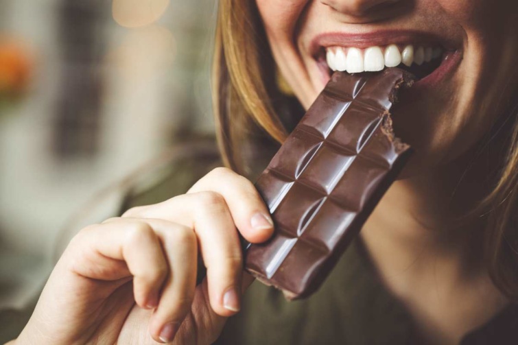 Egy tábla csokoládéba harap egy nő