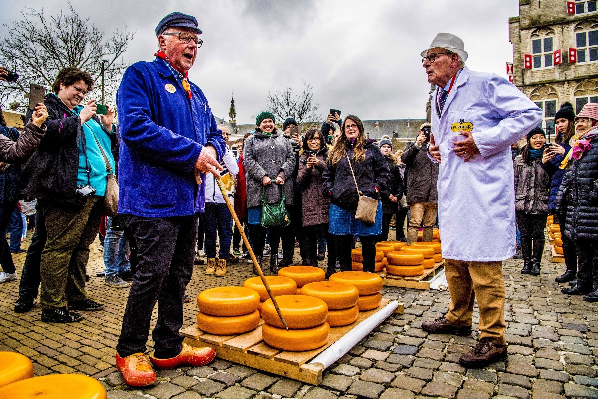 Hagyományos ruhát viselő sajtkészítők kínálják portékájukat a hollandiai Gouda sajtpiacán