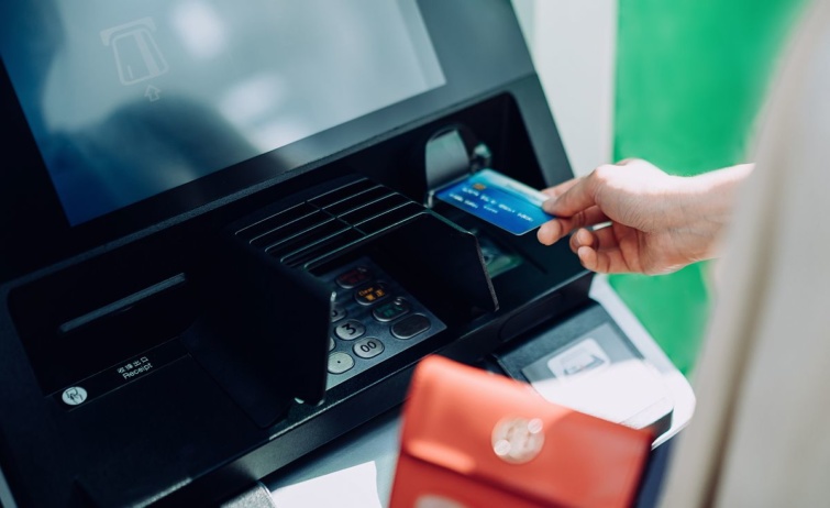 Egy kéz bankkártyát helyez a bankautomatába.