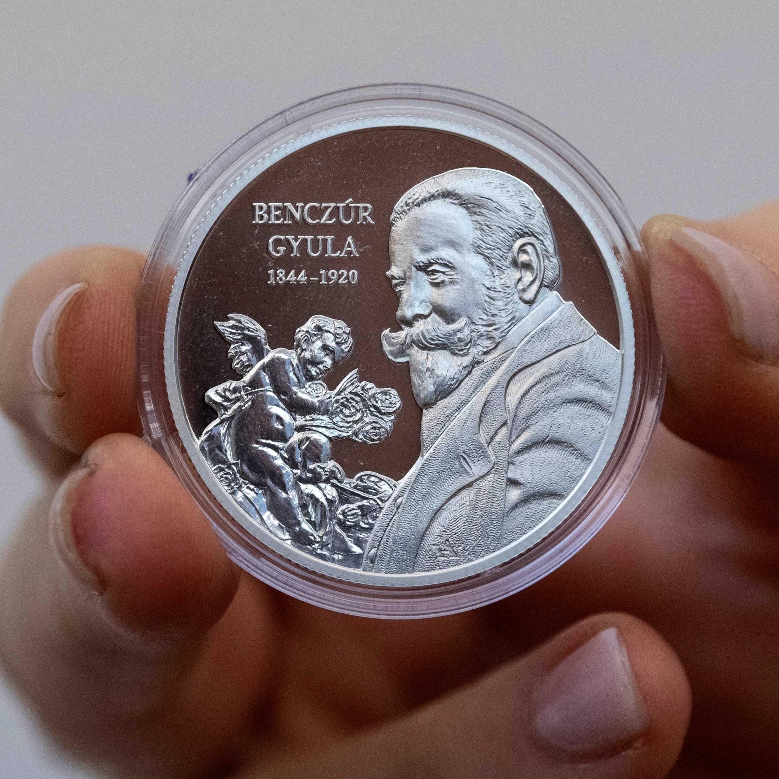 A Benczúr Gyula születésének 175. évfordulója tiszteletére készült, tízezer forint névértékű ezüst emlékérme hátoldala a hivatalos kibocsátási ünnepségen