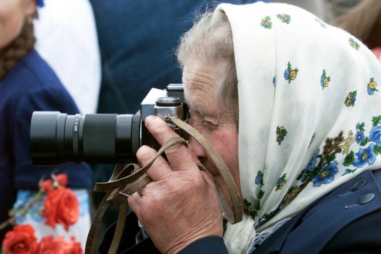 Idős hölgy fotót készít hagyományos kamerával 