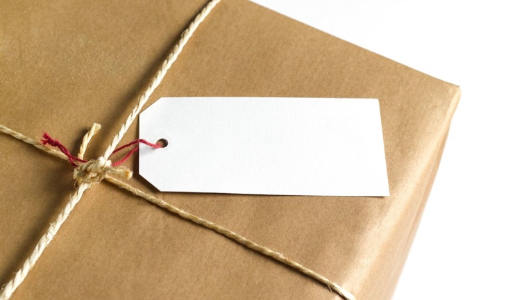 Egy csomagolópapírral bevont doboz átkötözve, üres ajándékkártyával.