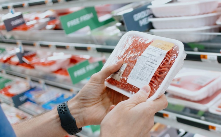 Egy vásárló egy tálca darálthúst tart a kezében a boltban.