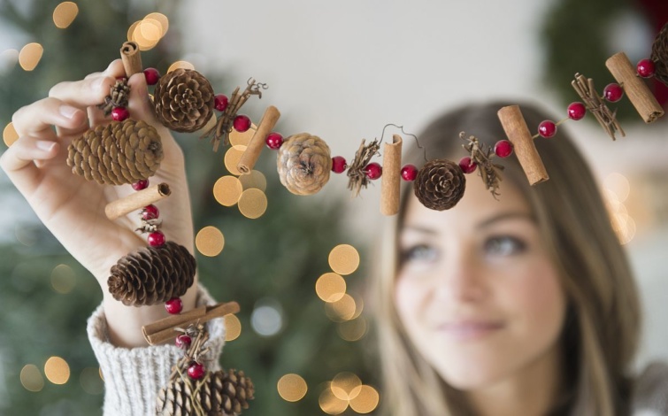 Egy nő karácsonyi dekorációval díszíti a lakást.