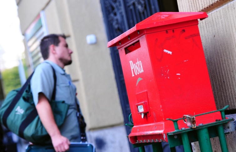 Egy postás egy postaláda mellett Magyarországon