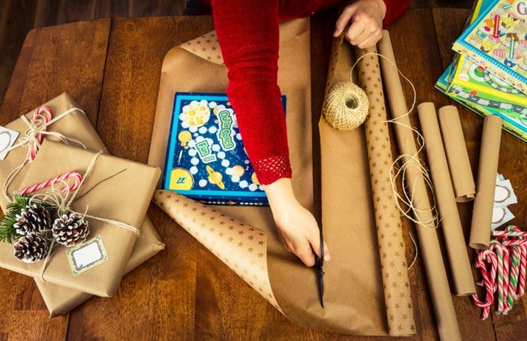 Egy piros ruhás nő ajándékot csomagol karácsonyra.