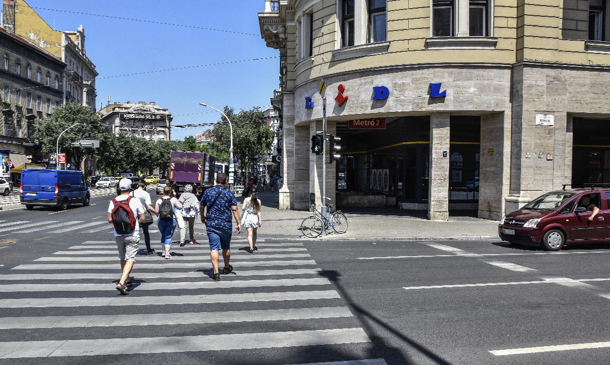 Gyalogosok haladnak a gyalogátkelőhelyen a Lidl élelmiszer-kereskedelmi hálózat áruház felé a fővárosban, a Blaha Lujza téren.