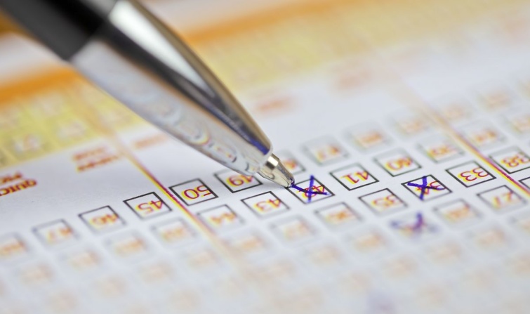 Egy töltőtoll számokat x-szel a lottószelvényen.