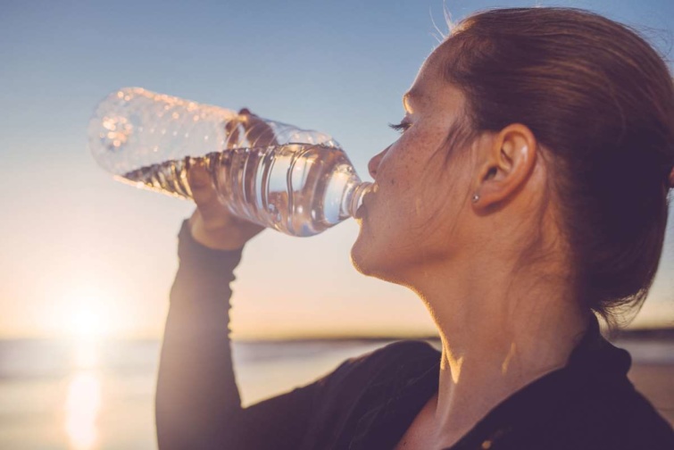 Palackozott vizet iszik a fiatal nő