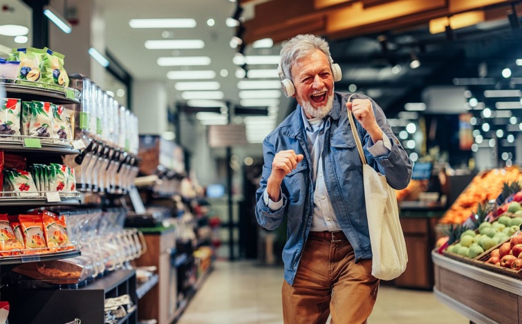 Egy idős férfi fejhallgatóval a fején táncol a boltban.