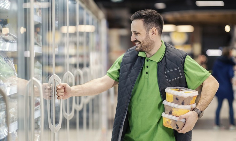 Jégkrémes dobozokat tart a kezében egy vásárló a boltban.