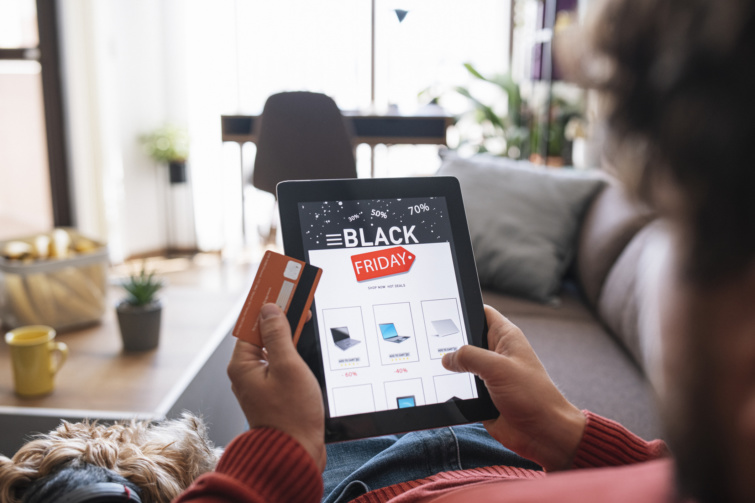black friday Startlap Vásárlás Férfi a kanapén fekve Black Friday akciókat böngész tableten