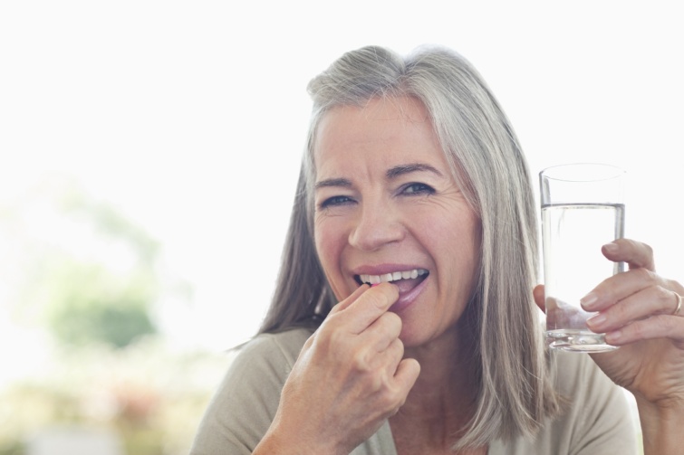 Egy nő tablettát vesz be vízzel