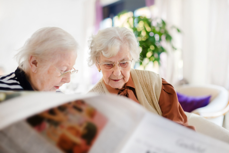 Két idős nő az idősek otthonában újságot olvas.