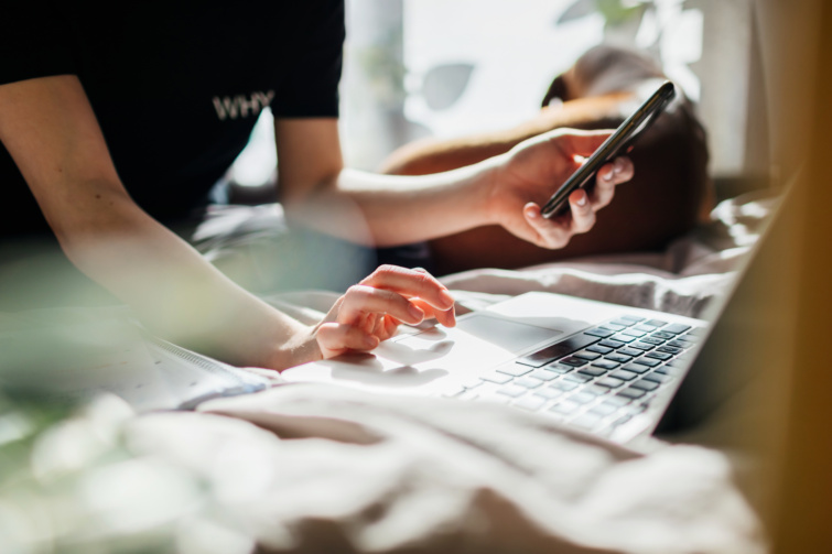 Fiatal lány mobiltelefonnal és laptoppal a kezében