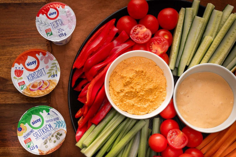 Asztalon tejfölök, felvágott zöldségek és körözött