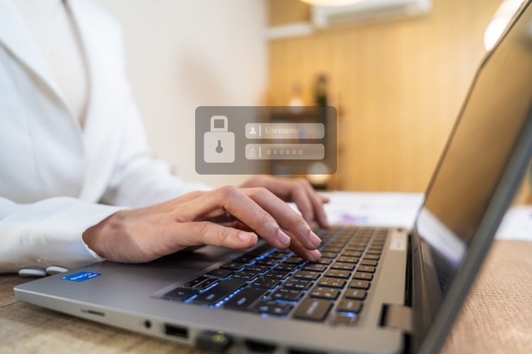 Laptopon dolgozó női kéz, felette kis ablakban felhasználónév és jelszó mező